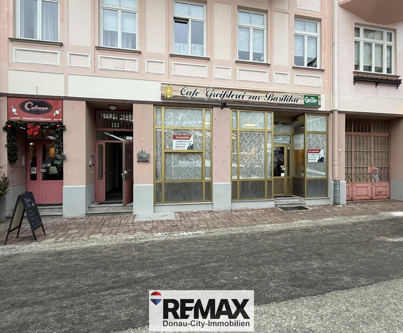 Die Fassade eines Geschäftsgebäudes mit großen Schaufenstern und Eingangsbereichen an einer Straße.