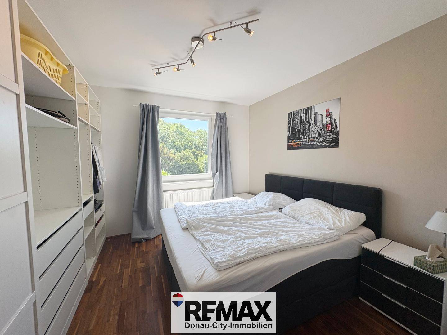 Schlafzimmer mit großem Doppelbett, Einbauschränken und Fenster mit Blick ins Grüne.