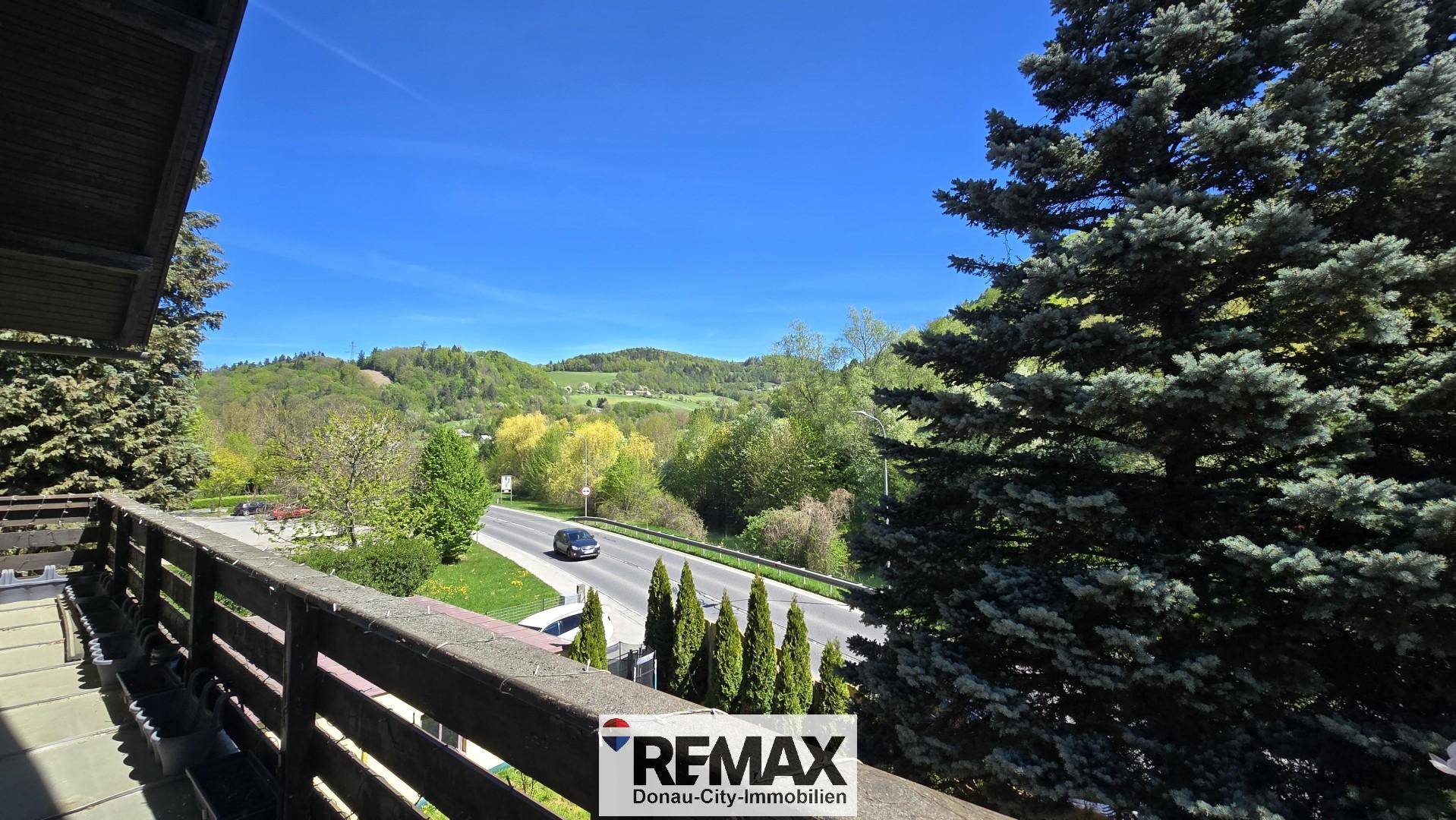 Balkon mit Holzbalkonbrüstung und weitem Blick auf die Landschaft und Straße.