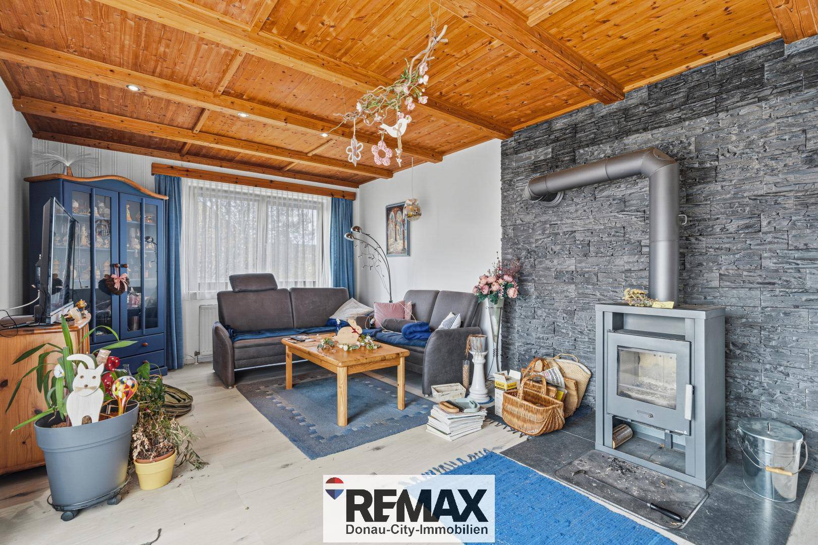 Gemütliches Wohnzimmer mit Holzbalkendecke, Kaminofen und rustikalem Charme.