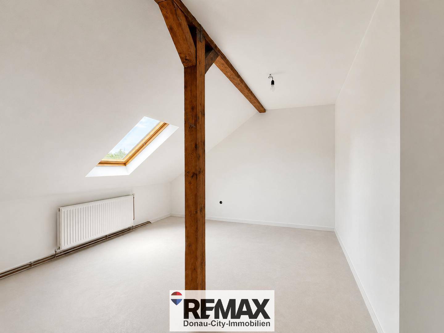 Helles Dachgeschosszimmer mit Dachschräge, sichtbarem Holzbalken und Dachfenster.