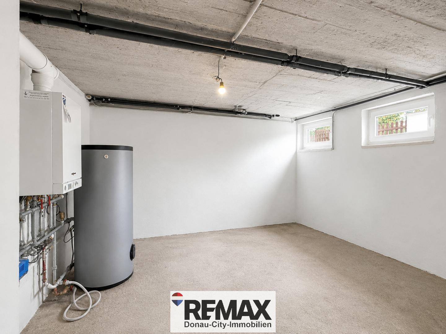 Heller Heizraum im Keller mit moderner Heizungsanlage und Warmwasserspeicher.