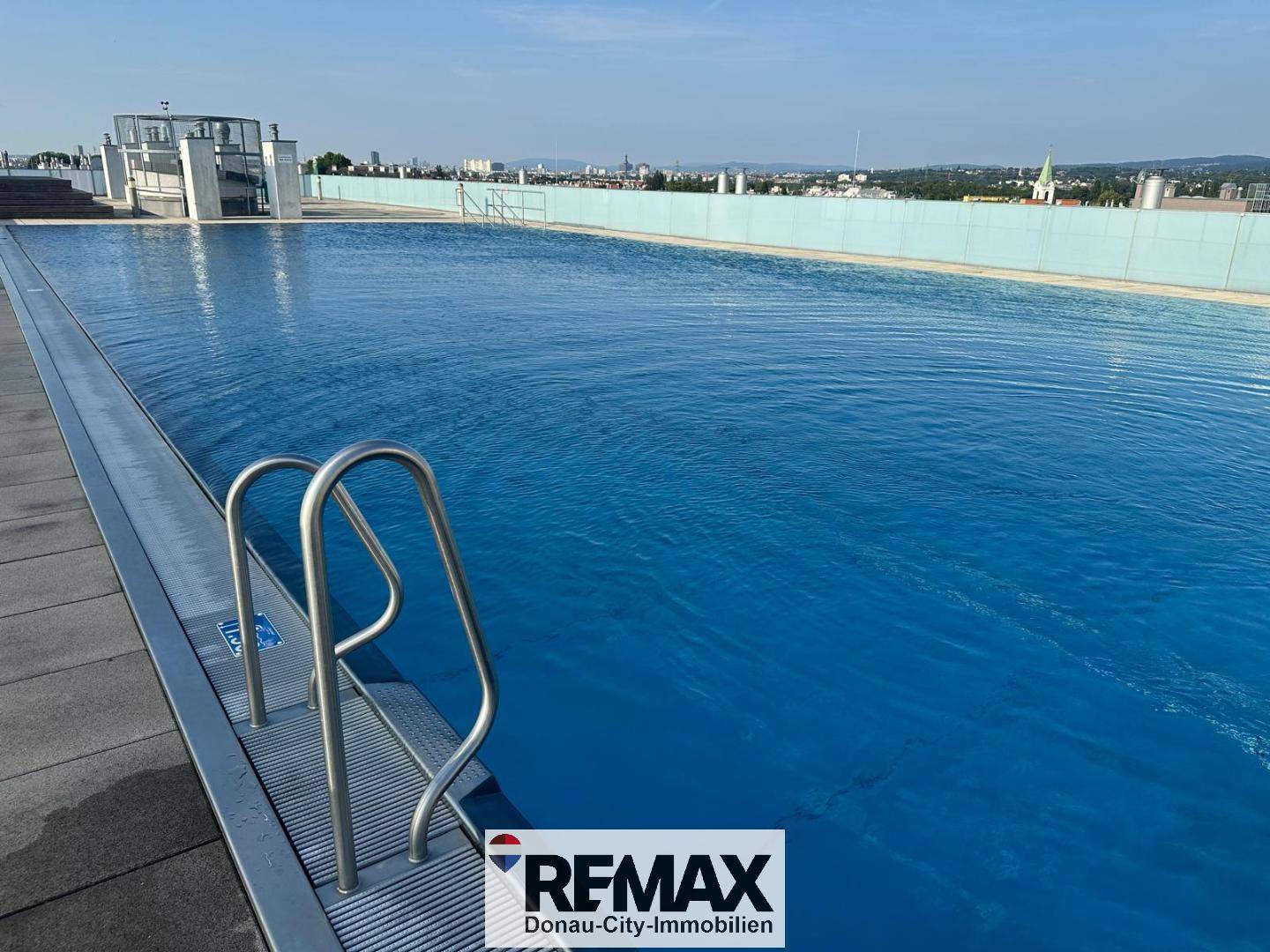 Dachpool mit Edelstahlleiter und weitem Blick über die Stadtlandschaft.