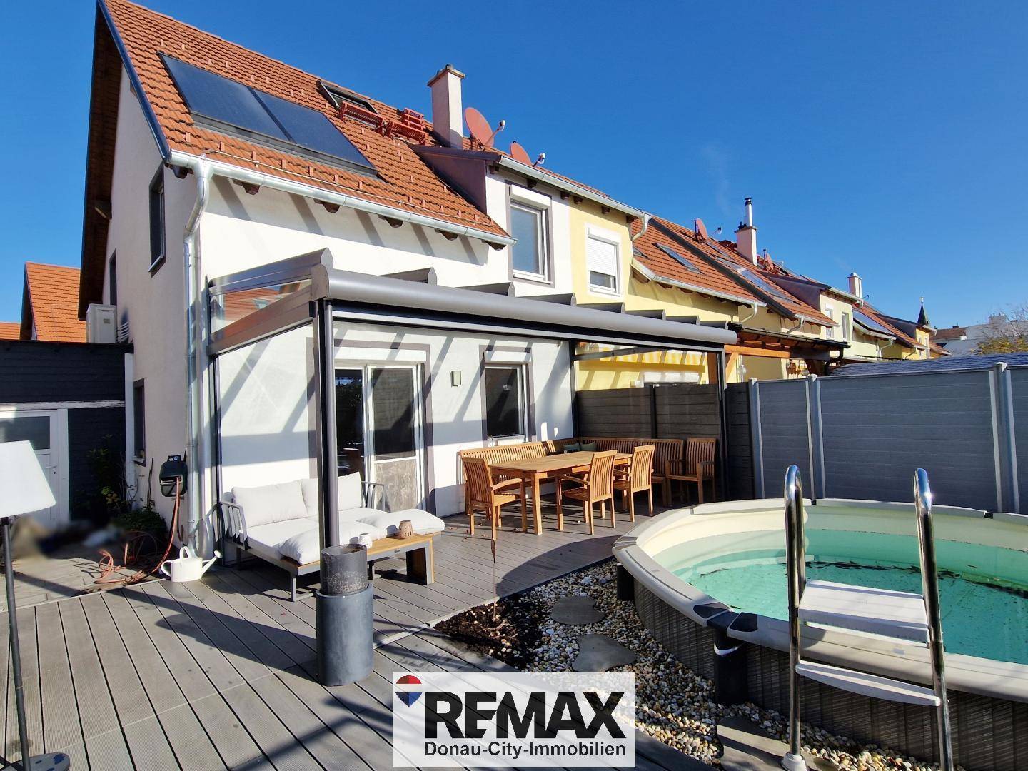 Rückansicht des Hauses mit sonniger Terrasse, Whirlpool und Photovoltaikanlage auf dem Dach.