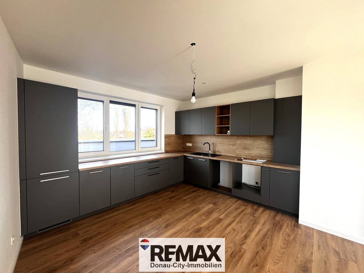 Moderne Einbauküche in Grau mit Holz-Arbeitsplatten und großem Fenster.