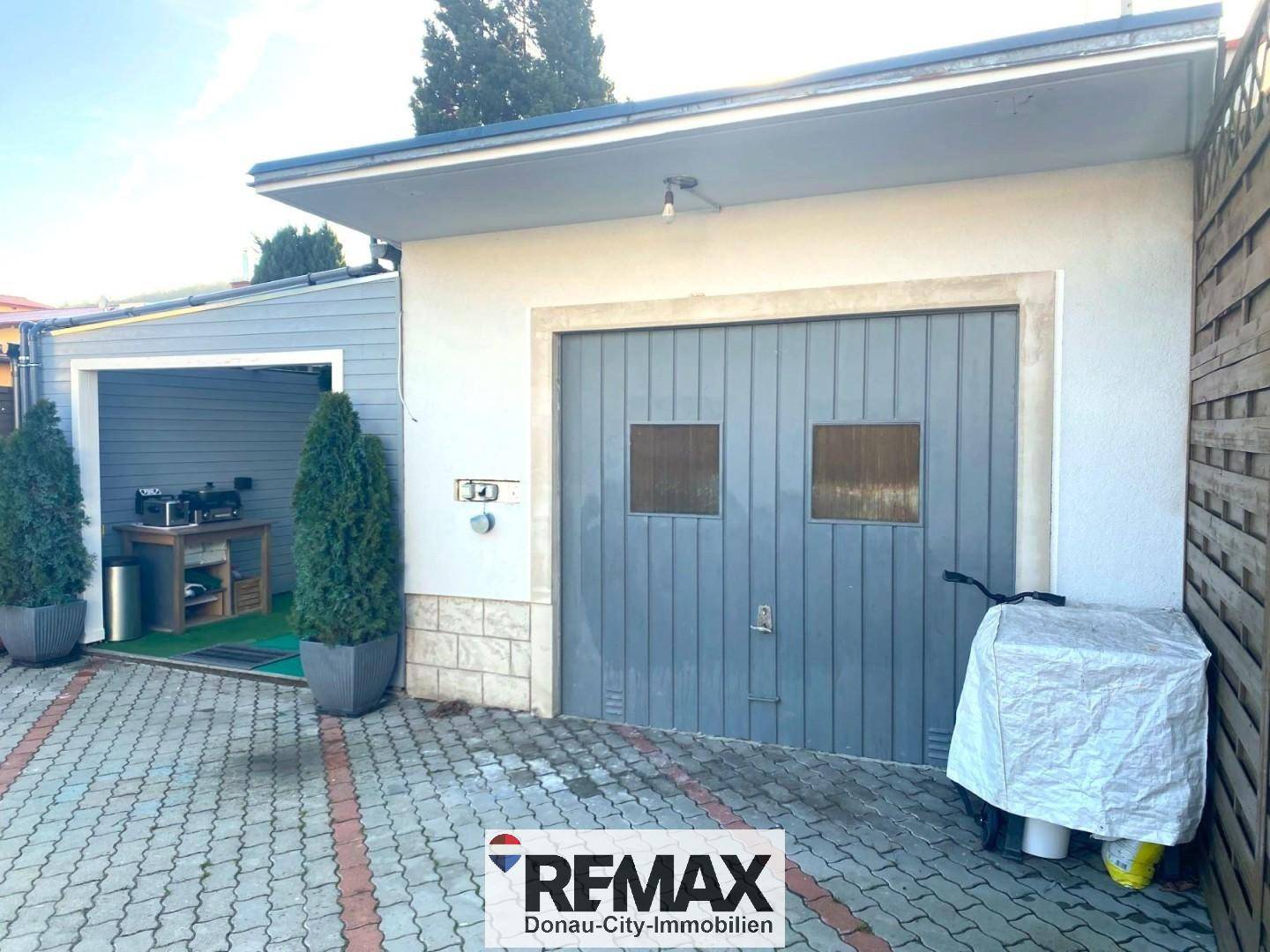Garage mit Holztor und angrenzendem überdachten Bereich, bietet viel Platz.