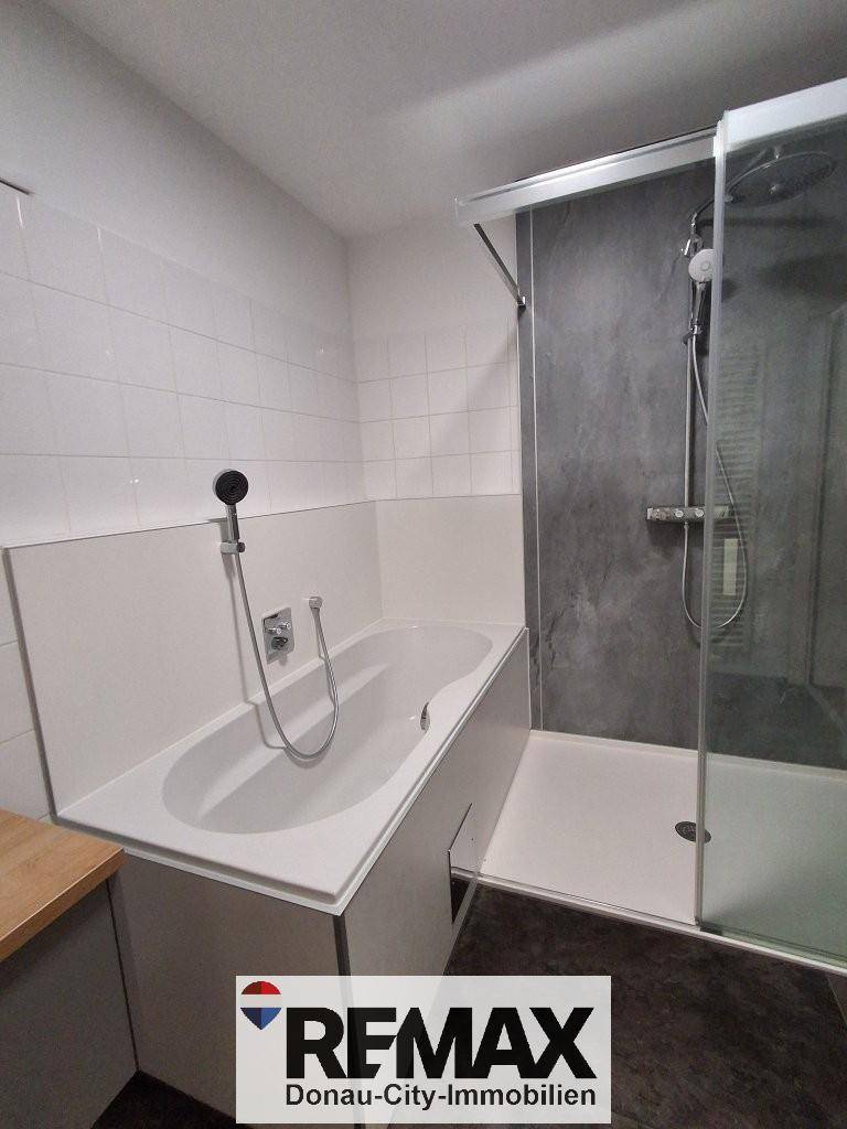 Badezimmer mit Badewanne, begehbarer Dusche und weißen Fliesen, modern und funktional gestaltet.