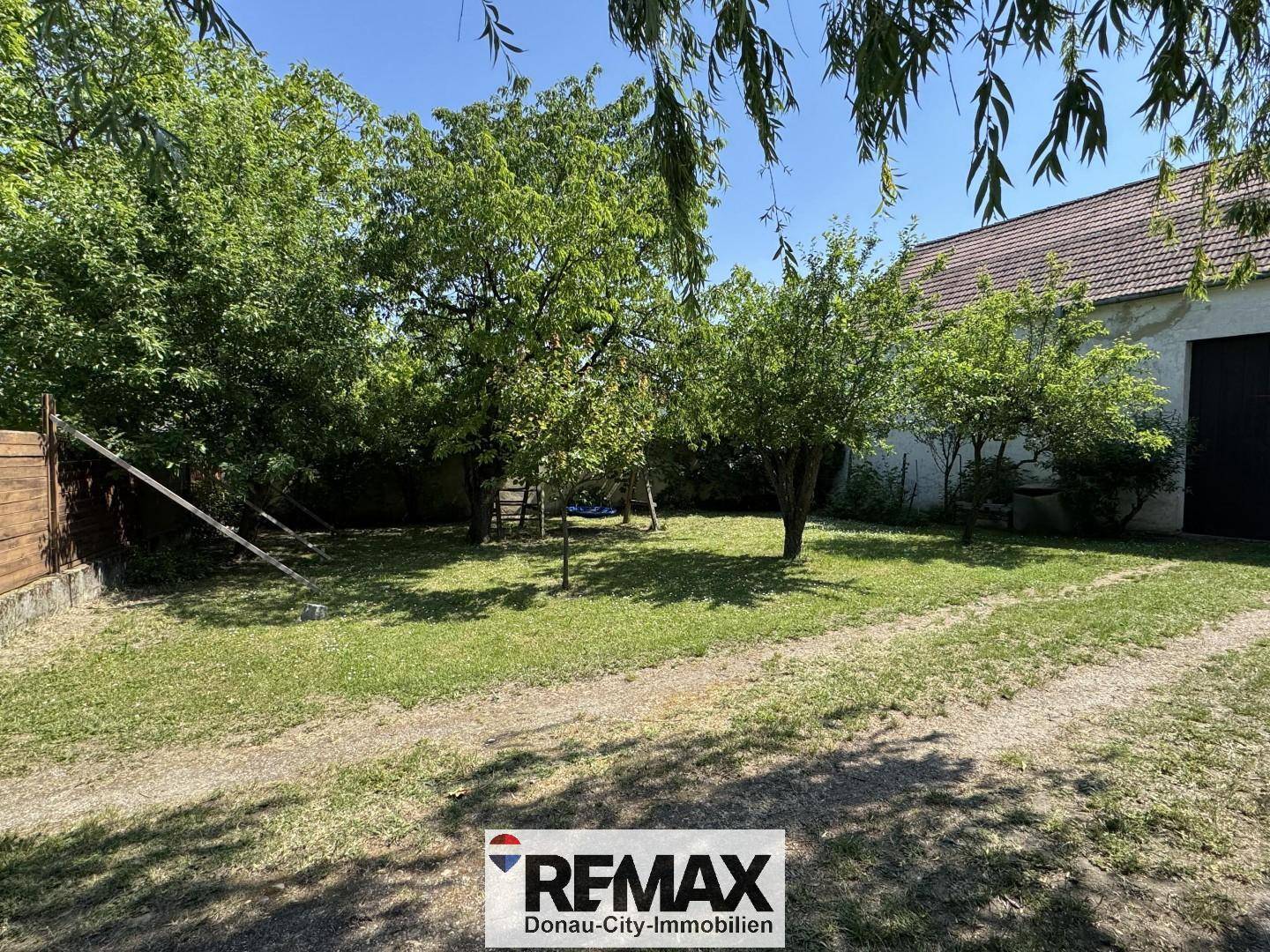 Grüner Garten mit Rasenfläche und Bäumen, bietet viel Platz im Freien und Privatsphäre.