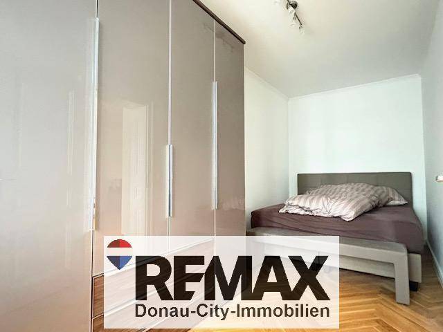 Gemütliches Schlafzimmer mit großem Einbauschrank und elegantem Parkettboden, bietet viel Stauraum.