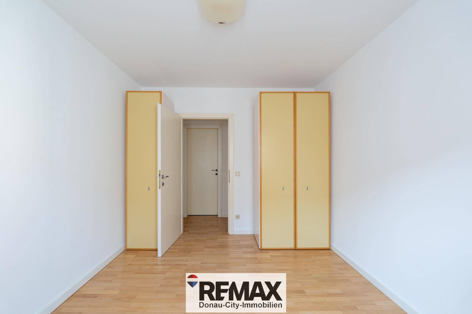 Schlafzimmer mit Parkettboden und zwei gelben Kleiderschränken.