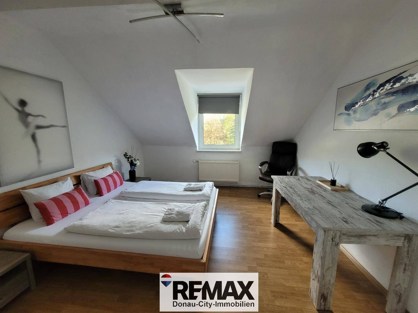 Gemütliches Schlafzimmer im Dachgeschoss mit Holzboden, Doppelbett und Schreibtisch.