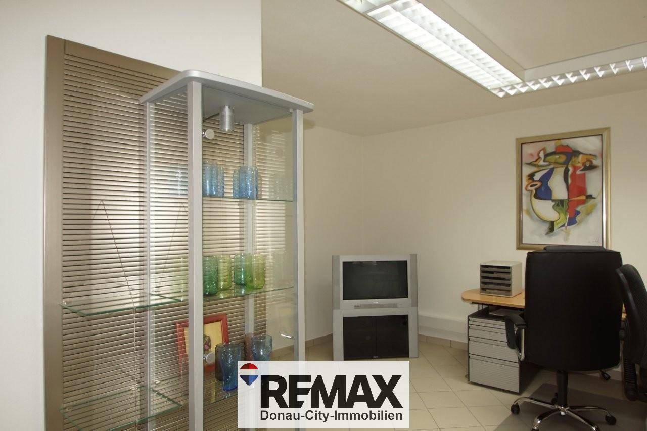 Büro mit Vitrine, Schreibtisch und Bürostuhl, bietet eine funktionale Arbeitsumgebung.