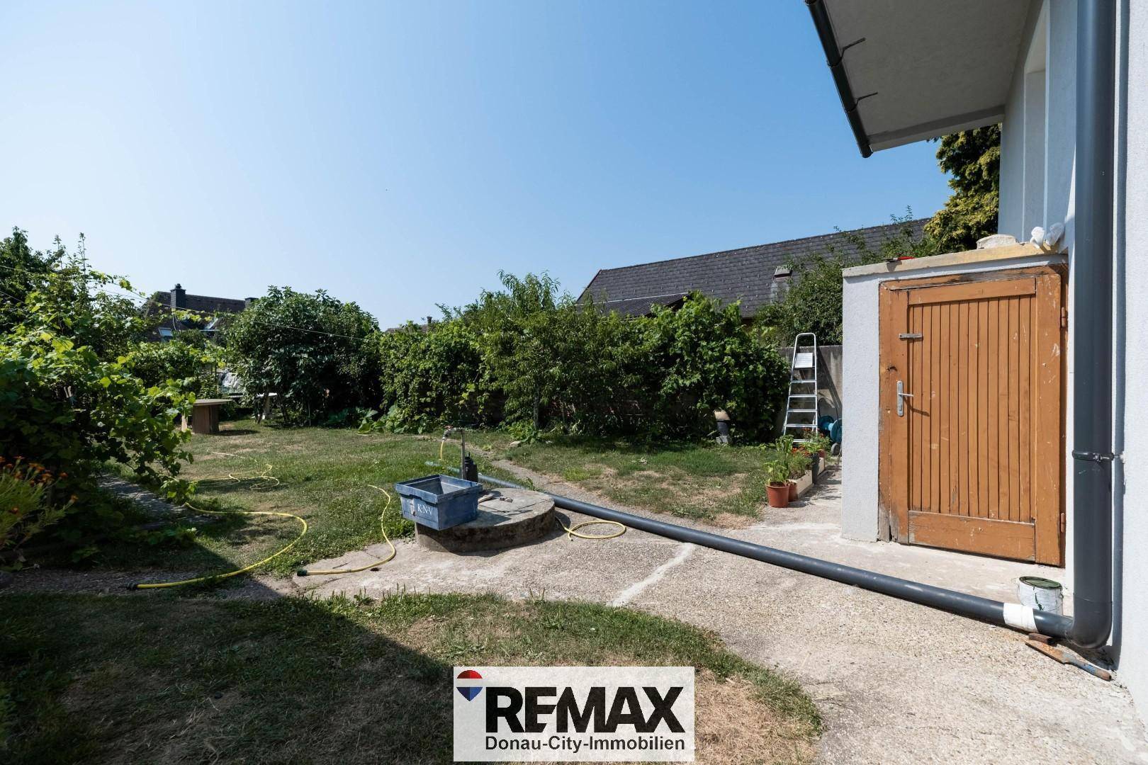 Garten mit Rasenfläche, Sträuchern und einem kleinen Schuppen am Haus.