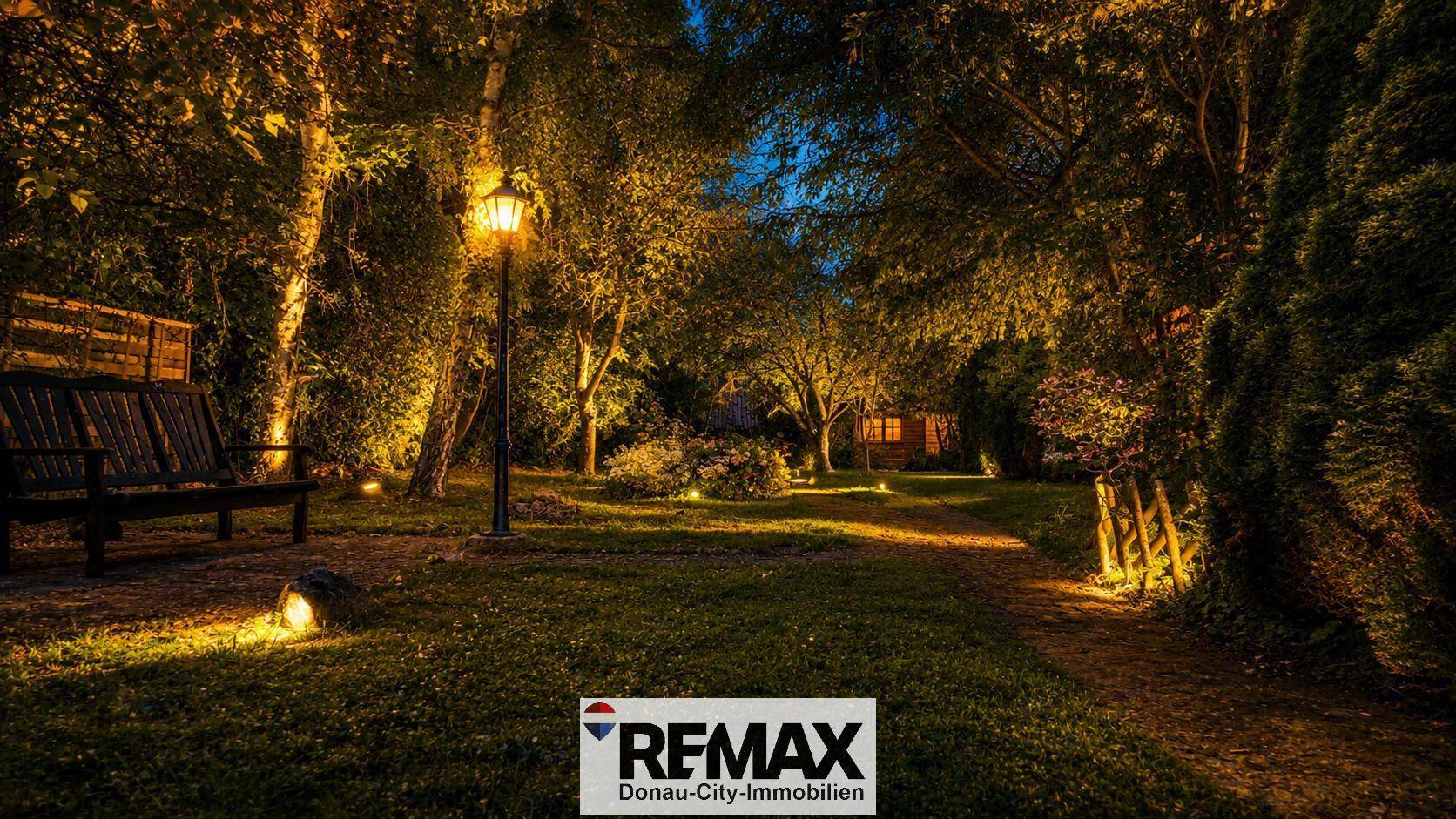 Stimmungsvoll beleuchteter Gartenbereich bei Nacht mit Sitzbank und Laternen.
