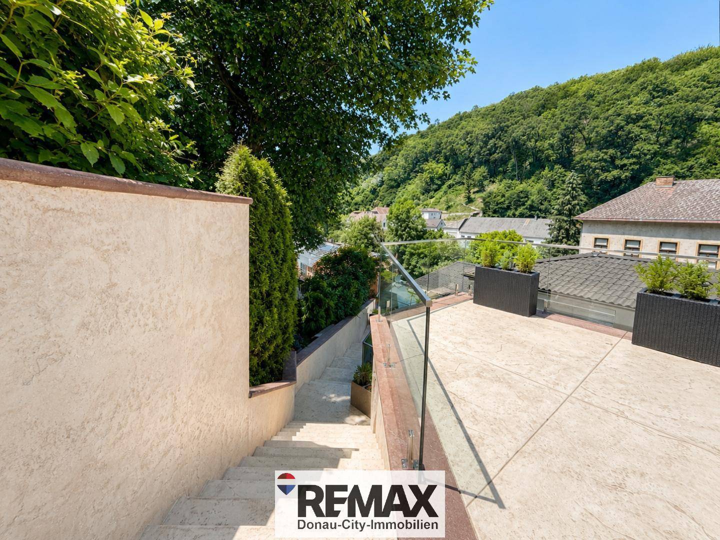 Außentreppe führt von der oberen Terrasse hinunter, umgeben von üppigem Grün.