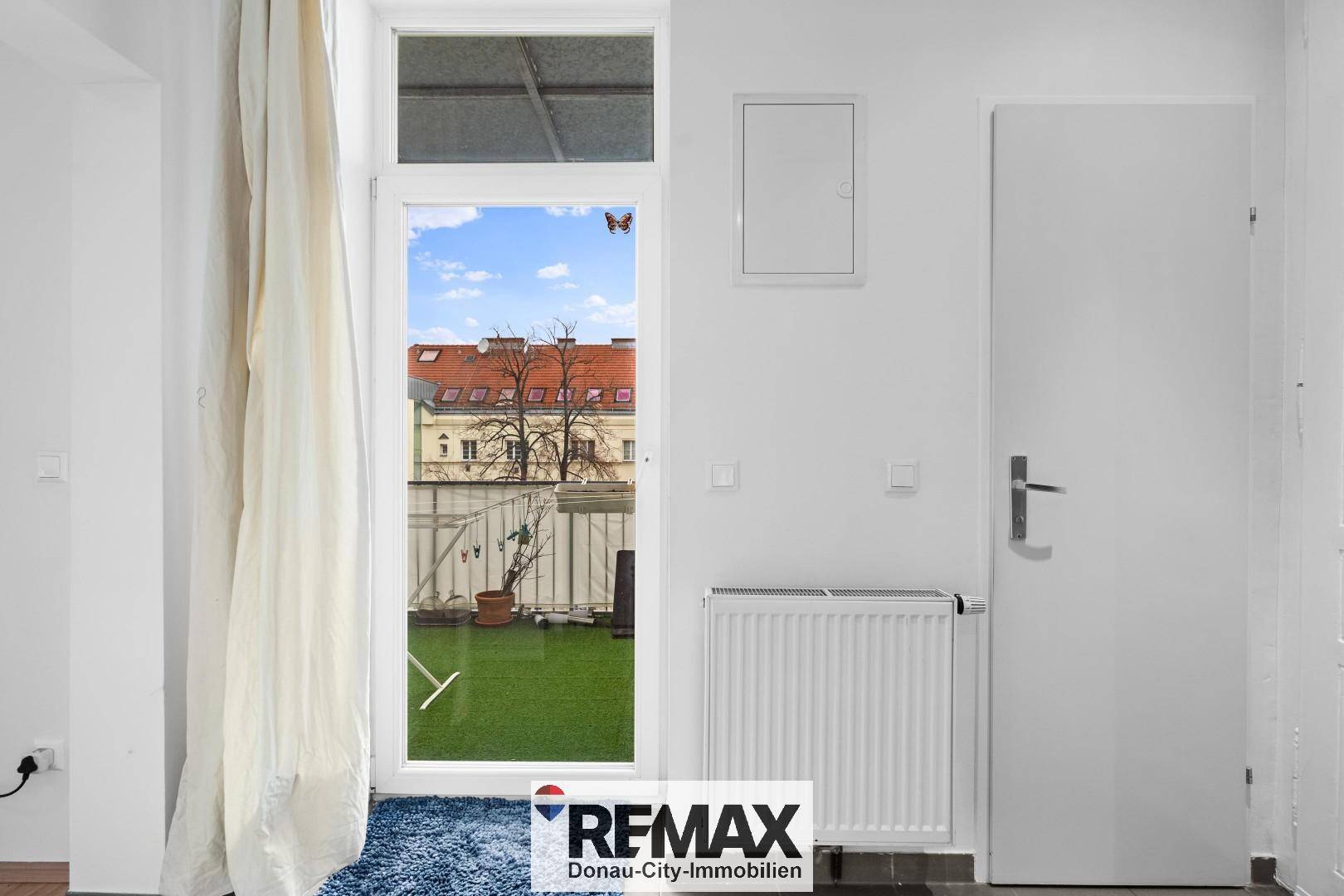 Innenbereich mit Zugang zum Balkon und Heizkörper unter dem Fenster.