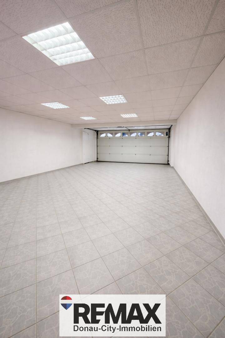 Geräumige, leere Garage mit Fliesenboden und einem großen Garagentor.