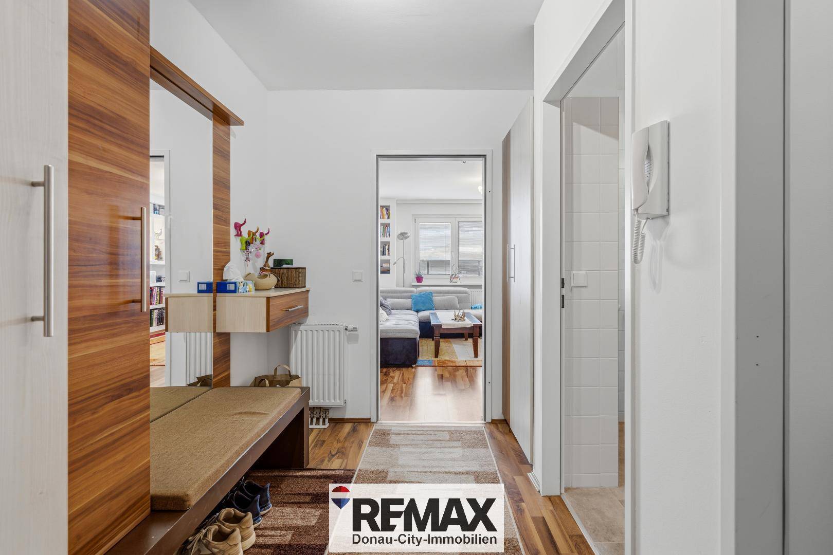 Einladender Flur mit Holzboden, Garderobe und Blick in den Wohnbereich.