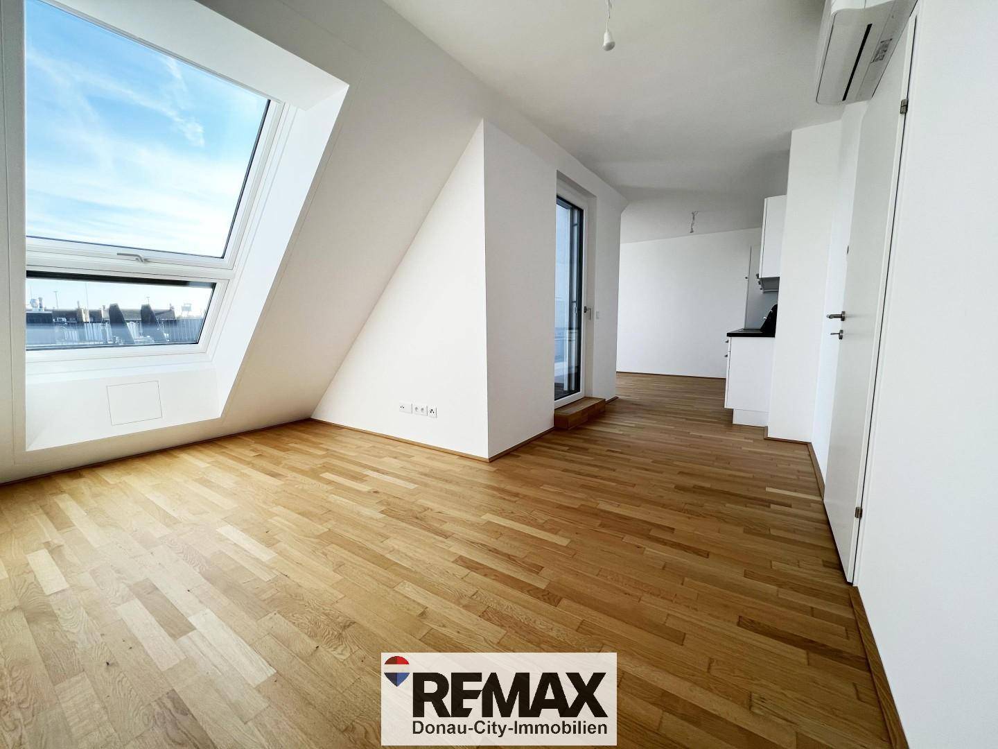 Geräumiges, leeres Wohnzimmer mit Holzboden und großen Dachfenstern, bereit zur individuellen Gestaltung.