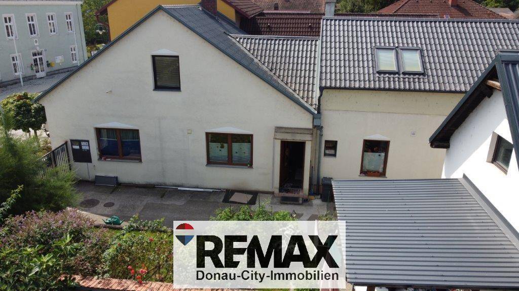 Ansicht eines Wohnhauses mit heller Fassade, Ziegeldach und einem gepflegten Gartenbereich im Vordergrund.