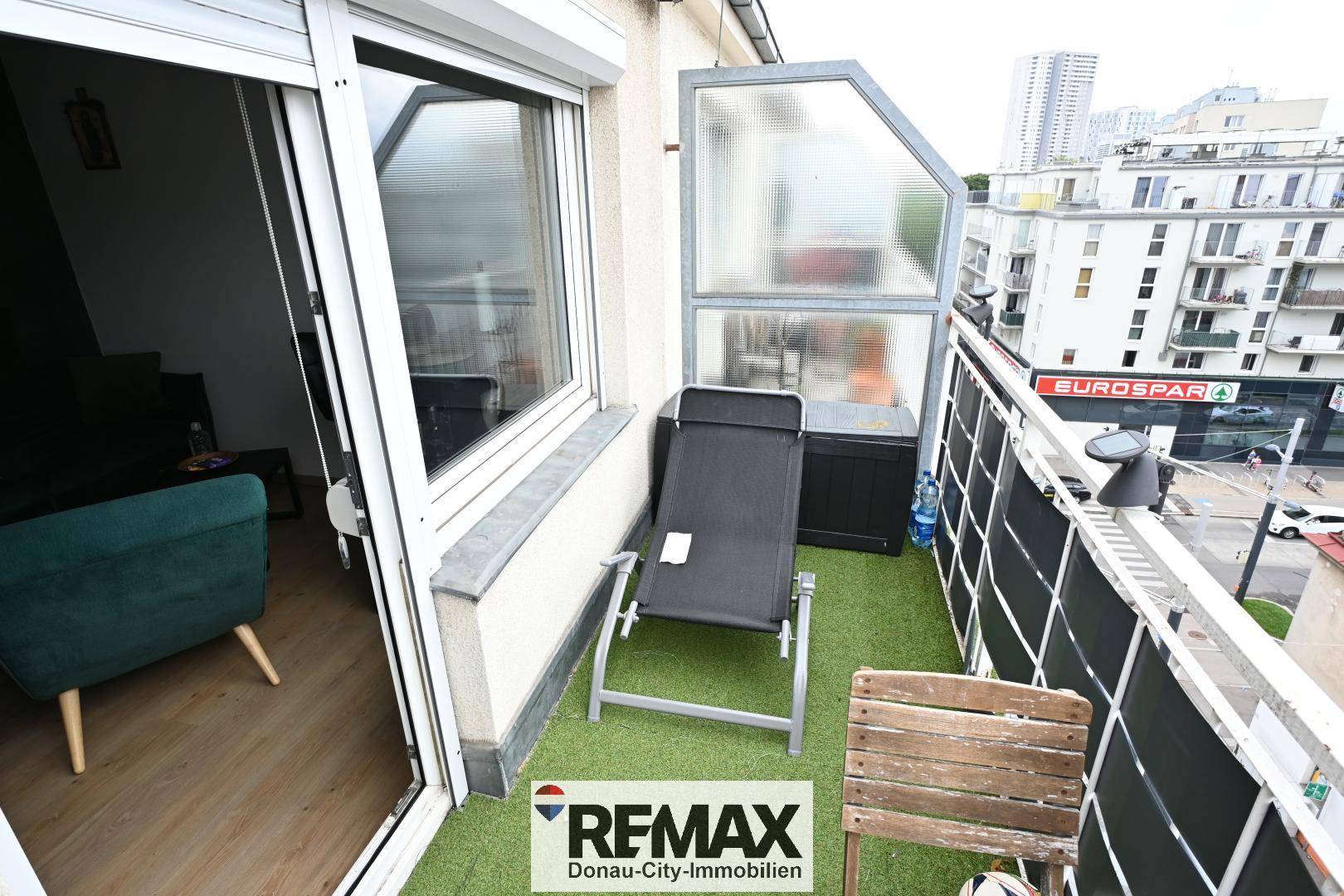 Balkon mit Sonnenliege und Blick auf die städtische Umgebung, ideal zum Entspannen.