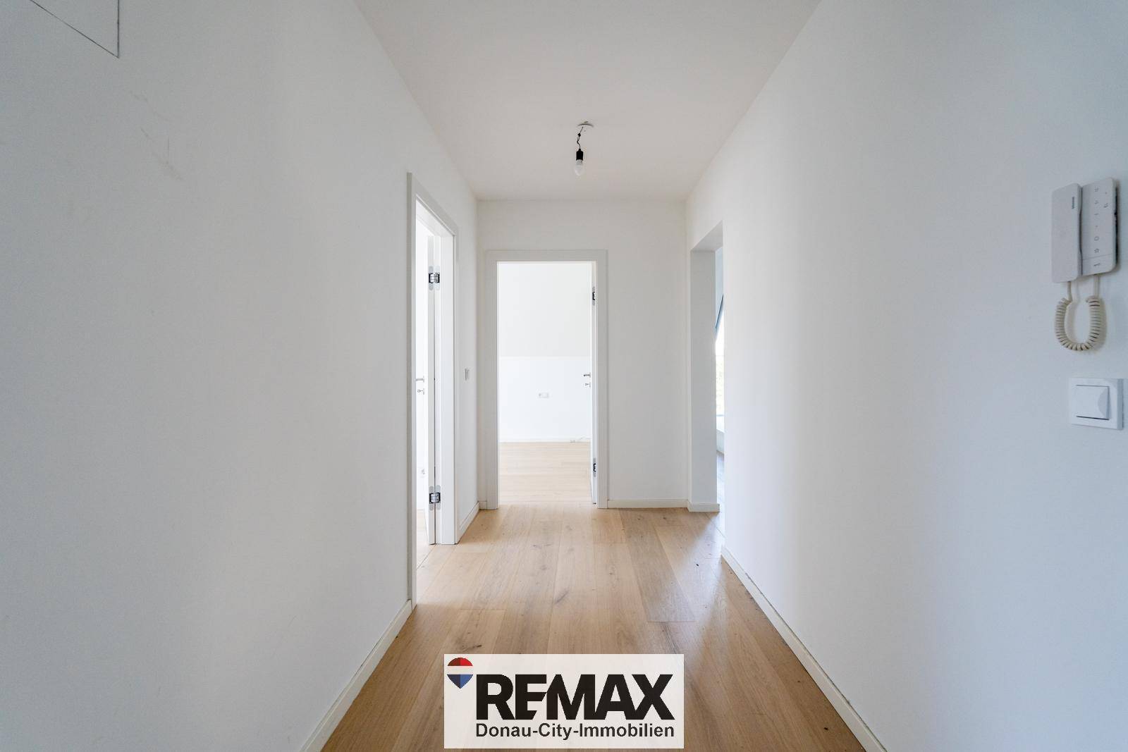 Heller Flur mit Holzfußboden, der zu den verschiedenen Zimmern der Wohnung führt.