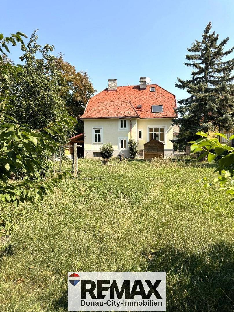 Das Einfamilienhaus von hinten, umgeben von einem weitläufigen, grünen Gartenbereich.