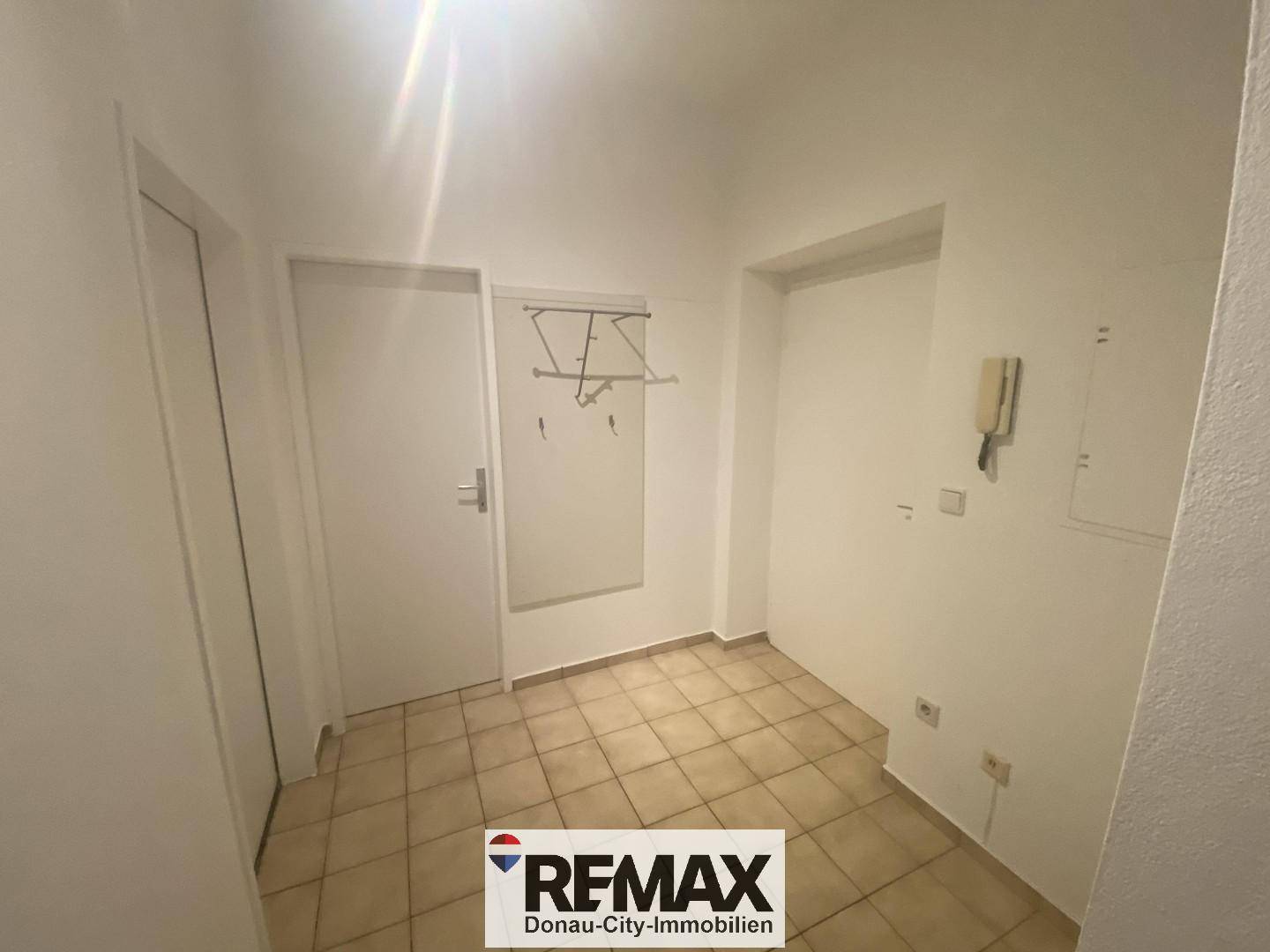 Eingangsbereich mit Fliesenboden, Garderobe und Gegensprechanlage, funktional gestaltet.