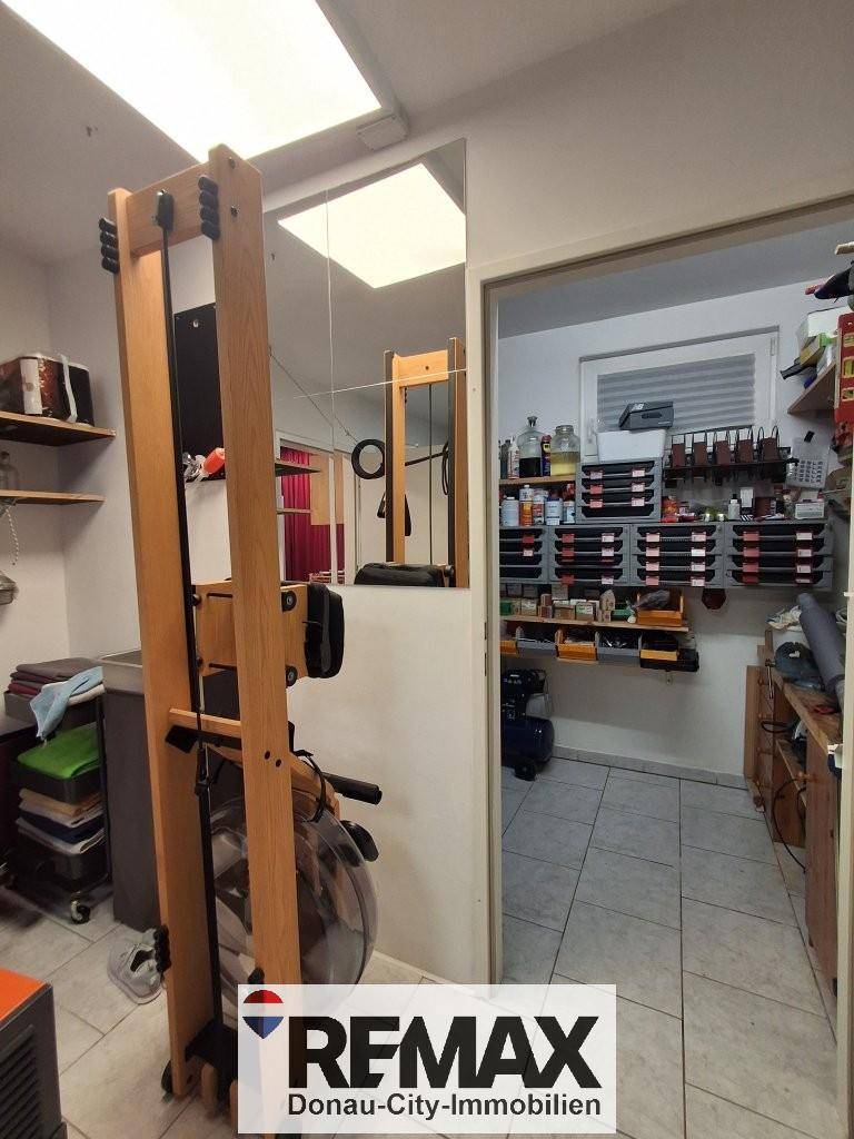 Kleiner Fitnessraum im Keller mit Rudergerät und angrenzendem Abstellraum.