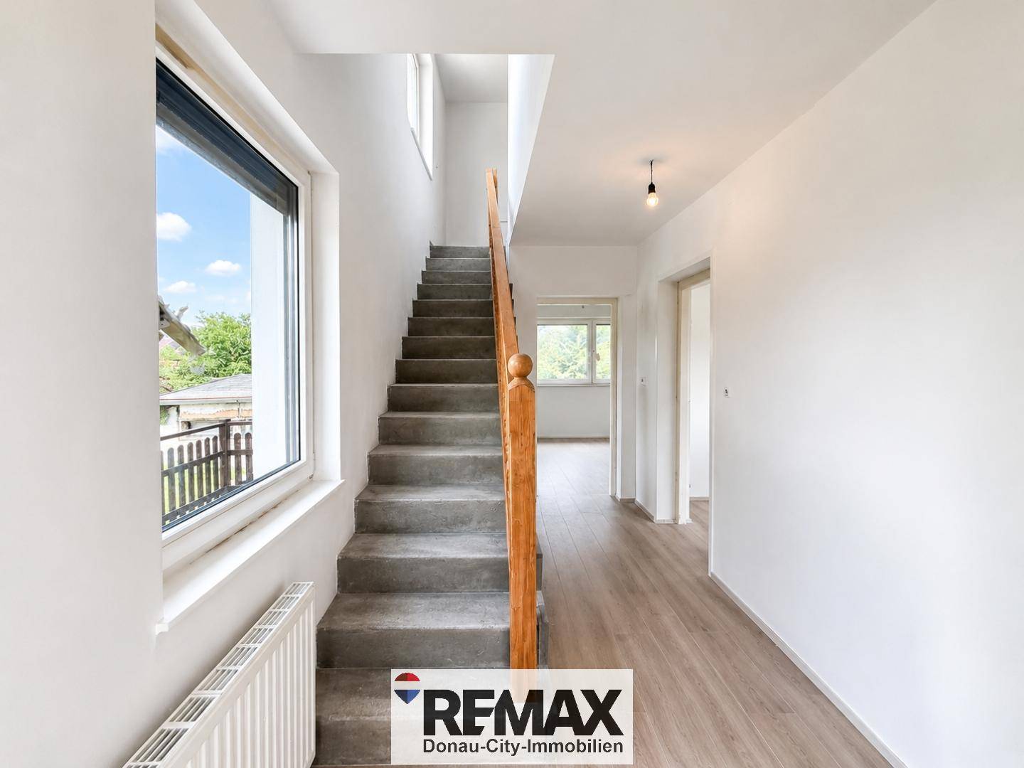 Heller Flur mit Treppe, großem Fenster und neuem Laminatboden.