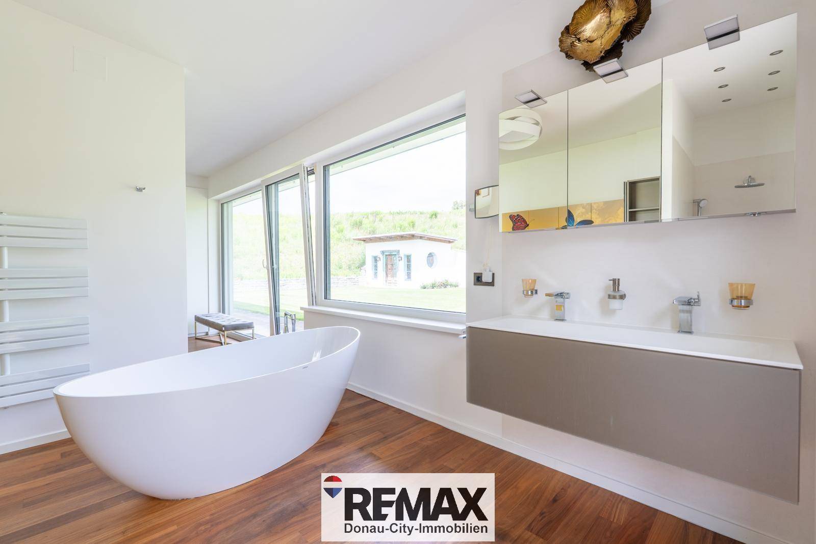 Modernes Badezimmer mit freistehender Badewanne, Doppelwaschbecken und großen Fenstern.