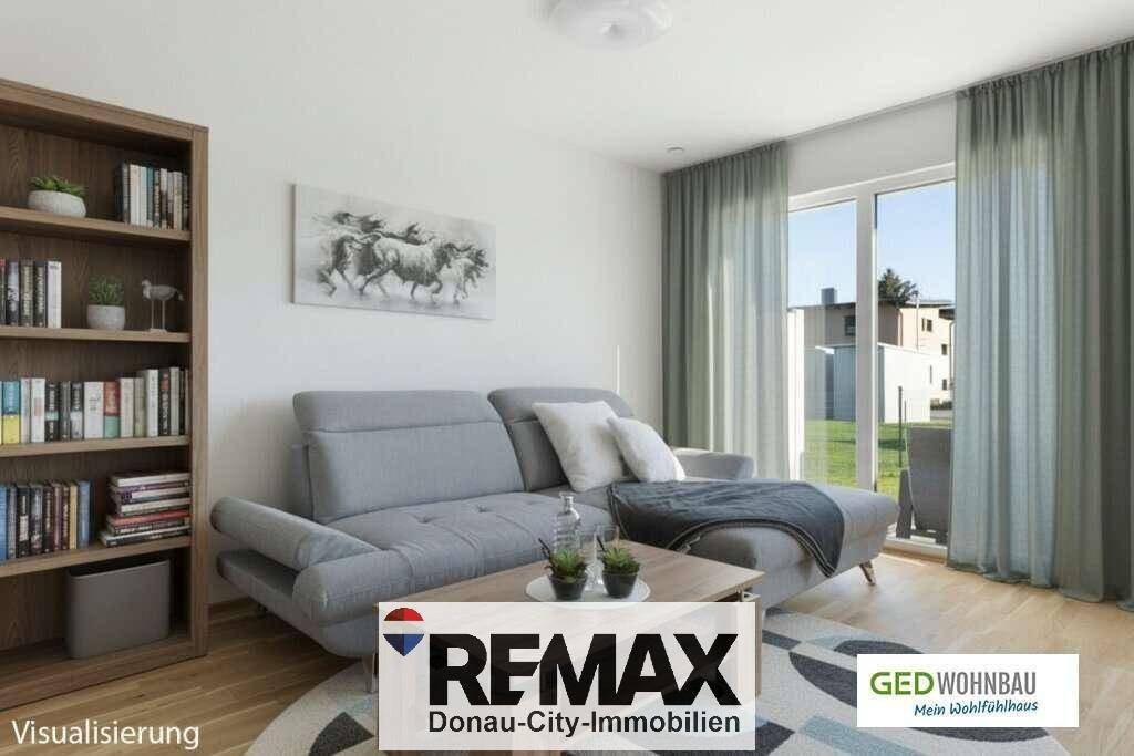 Gemütliches Wohnzimmer mit grauem Sofa, Bücherregal und großem Fenster für viel Tageslicht.