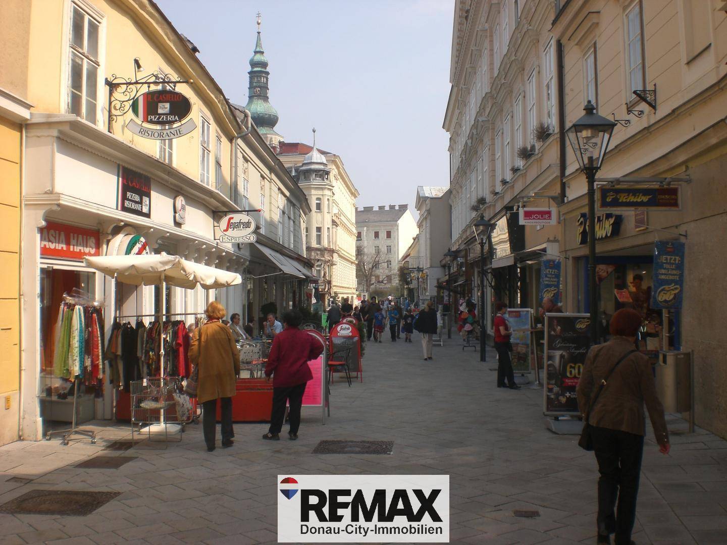 Belebte Fußgängerzone mit Geschäften, Restaurants und Passanten, typisch für die Stadtumgebung.