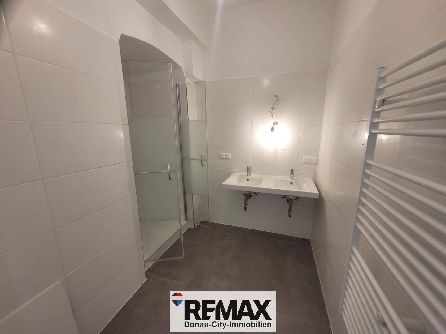 Modernes Badezimmer mit großer Duschkabine, Doppelwaschbecken und beheiztem Handtuchhalter.