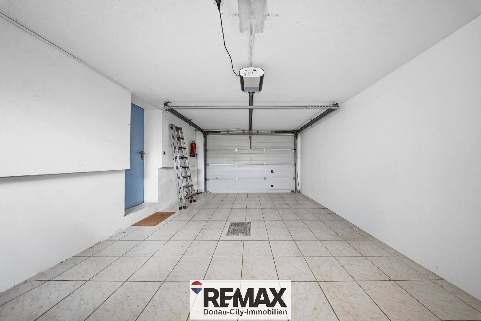 Geräumige Garage mit Fliesenboden und automatischem Garagentor, bietet Platz für ein Fahrzeug.