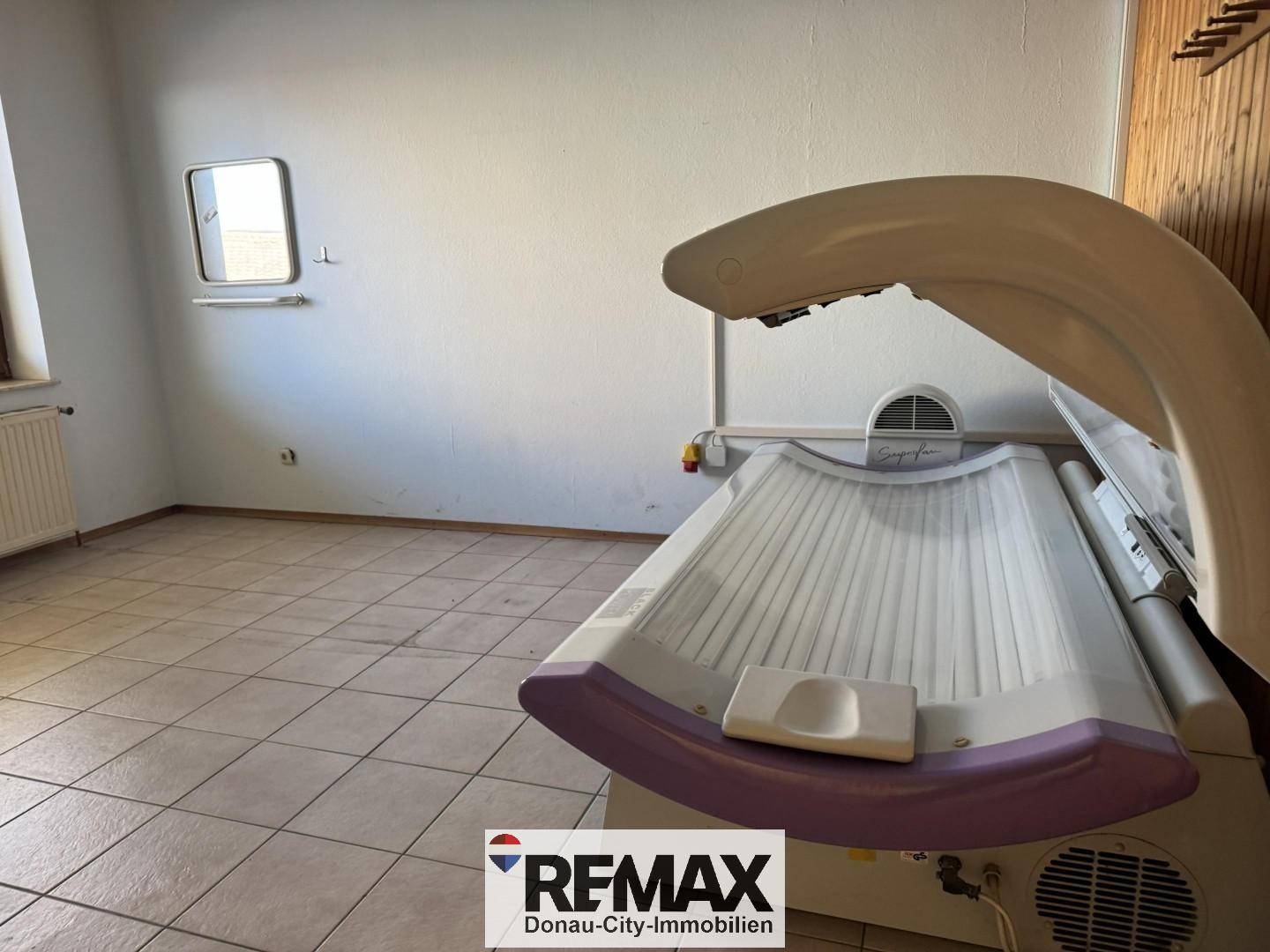 Heller Raum mit Fliesenboden und einem Solarium, ideal für einen privaten Wellnessbereich im Haus.