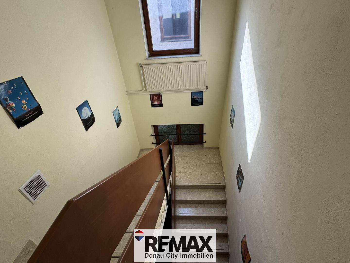 Treppenhaus mit einem Fenster im oberen Bereich, das für natürliches Licht sorgt und die Etagen verbindet.