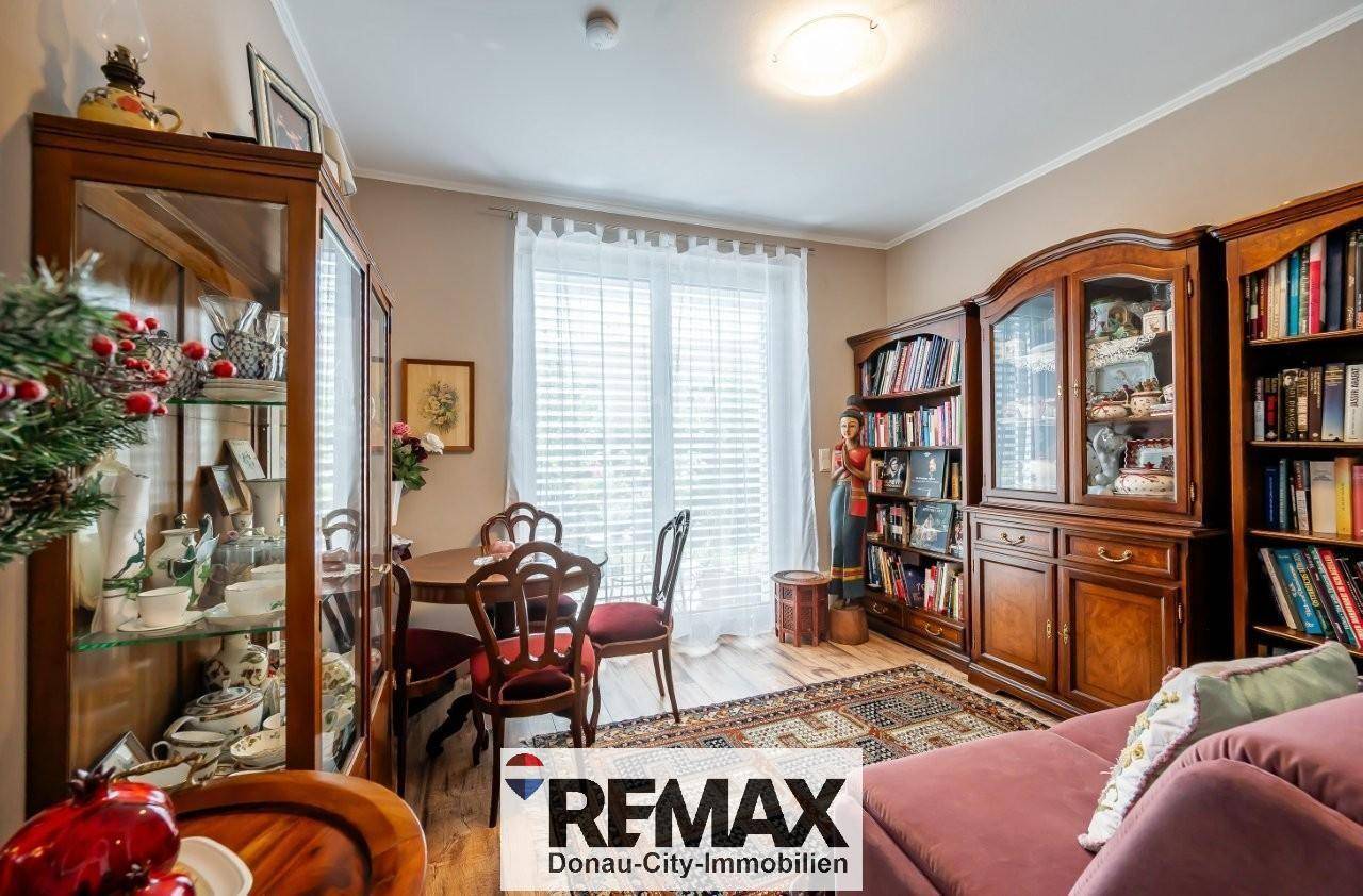 Traditionell eingerichteter Wohn- und Essbereich mit Holzboden, Vitrinen und einem gemütlichen Sofa.