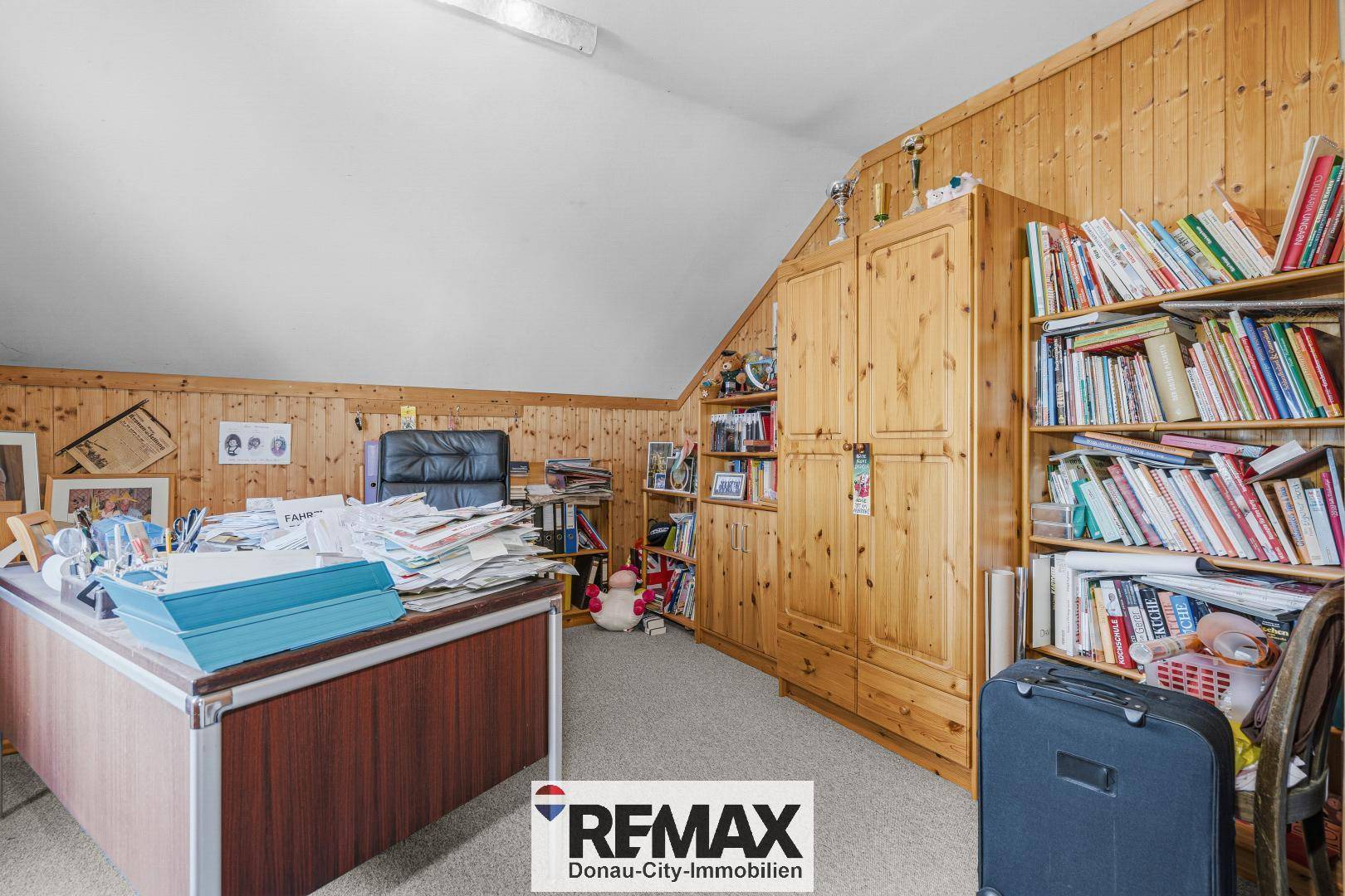 Arbeitszimmer mit Holzvertäfelung, integrierten Bücherregalen und viel Stauraum.