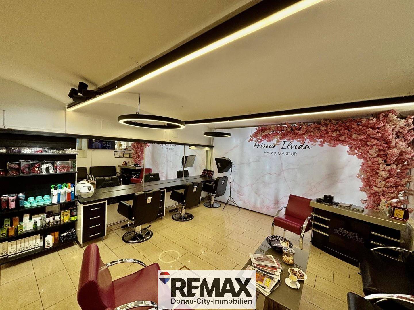 Friseursalon mit Produktregalen, Styling-Bereichen und einer dekorativen Wandgestaltung mit Kirschblütenmotiv.