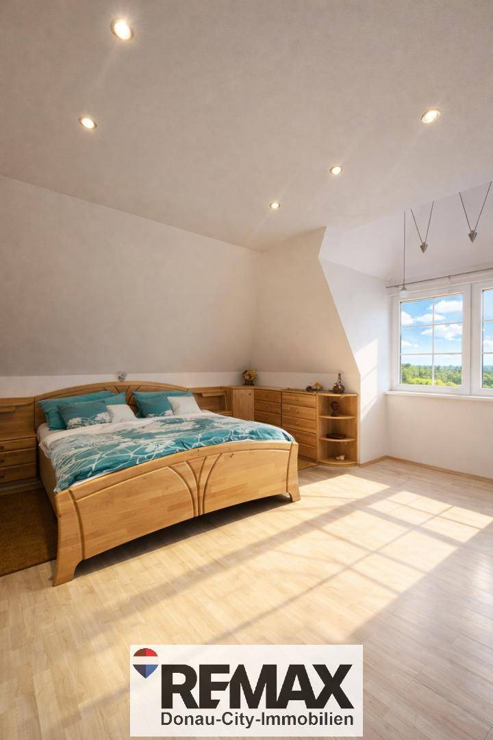 Helles Schlafzimmer mit Holzdoppelbett, Nachttischen, Kommoden und Fenster mit Blick ins Grüne.