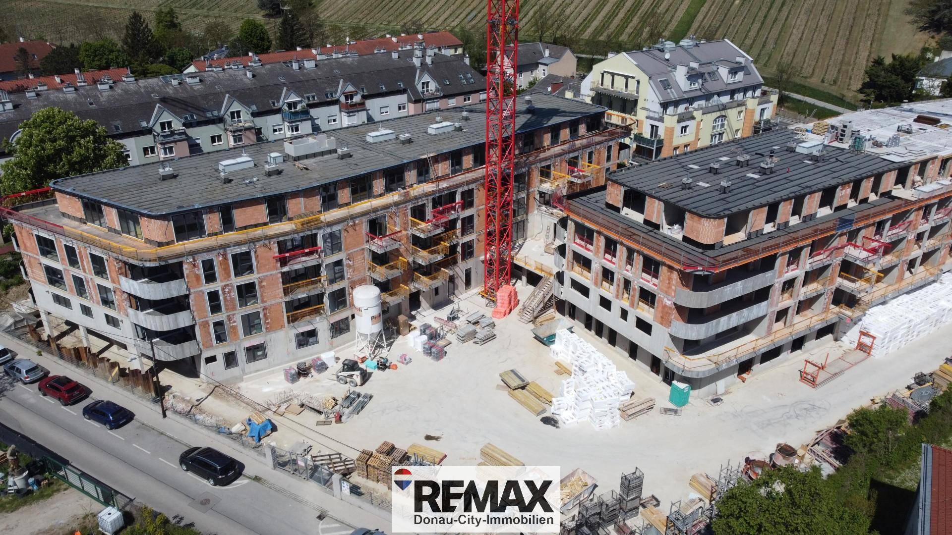 Luftaufnahme einer Baustelle mit zwei im Bau befindlichen Mehrfamilienhäusern und Kränen.