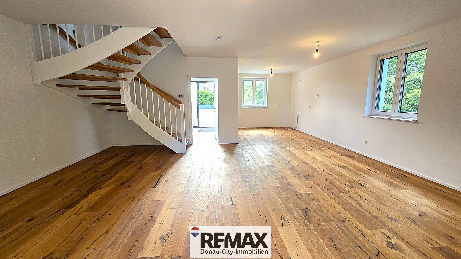 Heller Wohnbereich mit Holzparkett und moderner Treppe, bereit zur individuellen Einrichtung.