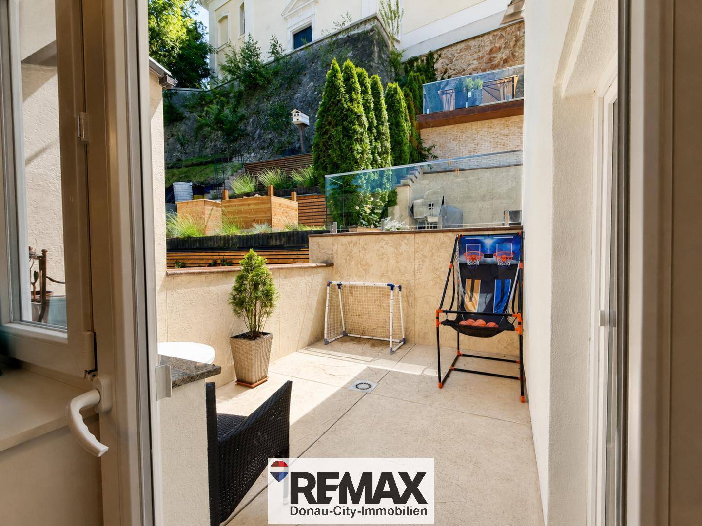 Kleiner Terrassenbereich mit Sportgeräten und Blick auf die gestuften Gartenanlagen.