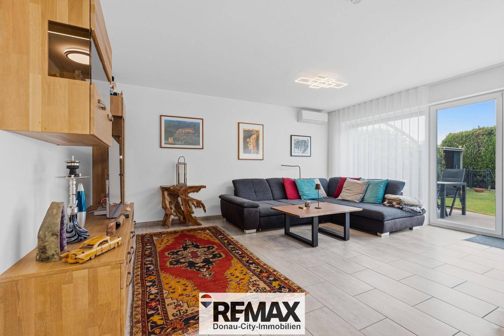 Gemütliches Wohnzimmer mit großem Sofa, Teppich und Zugang zum Garten, hell und modern eingerichtet.