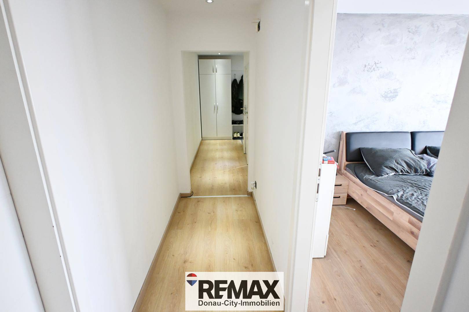 Heller Flur mit Laminatboden, der zu einem Schrankbereich und dem Schlafzimmer führt.