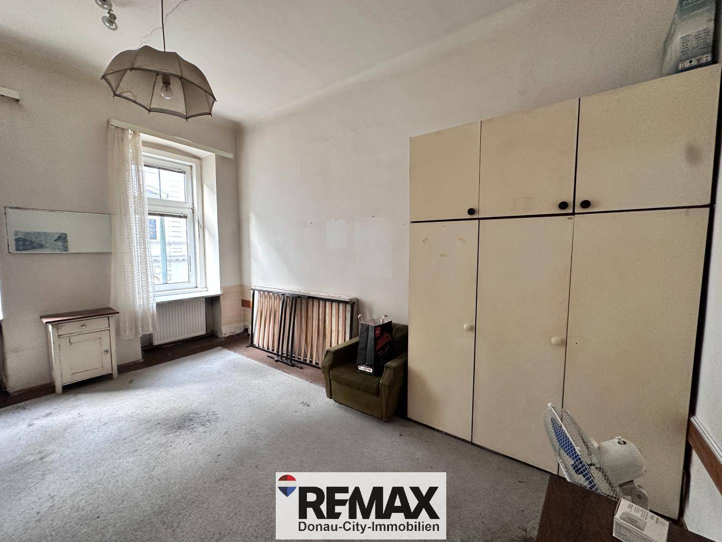 Schlafzimmer mit Teppichboden, großem Kleiderschrank und einem Fenster zur Straße.