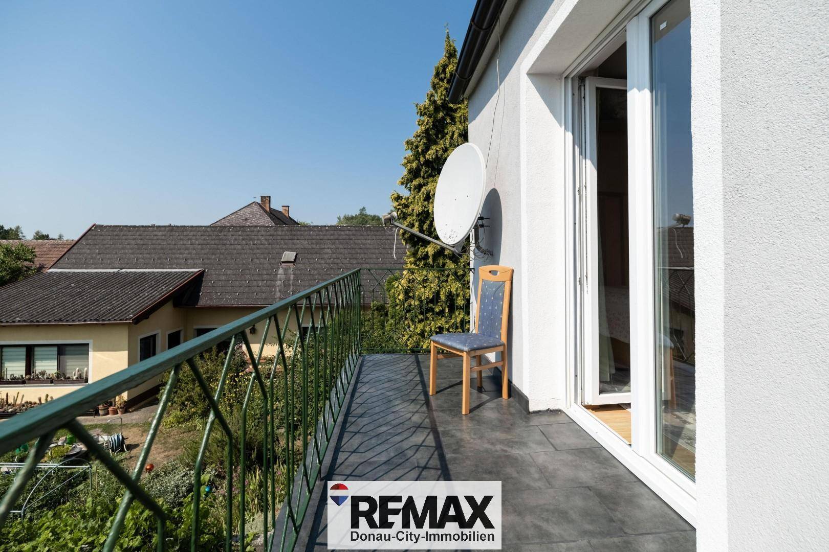 Kleiner Balkon mit Metallgeländer und Blick auf die umliegenden Häuser und Gärten.