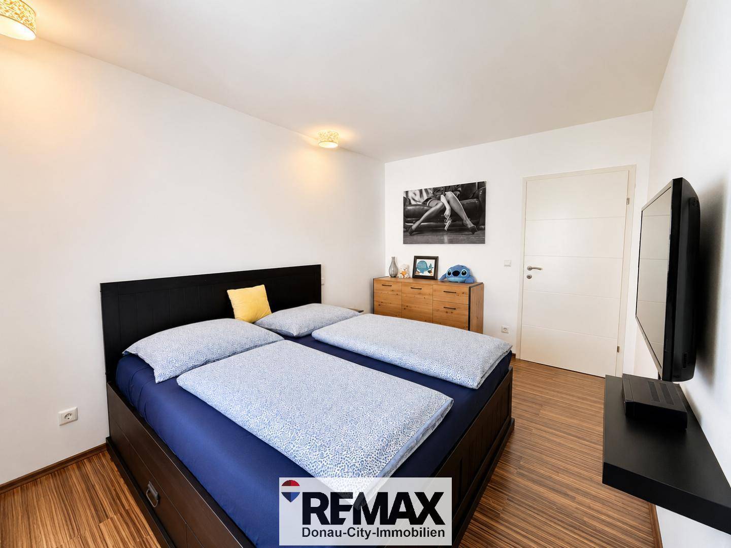 Schlafzimmer mit großem Bett, Holzboden und moderner Dekoration an der Wand.