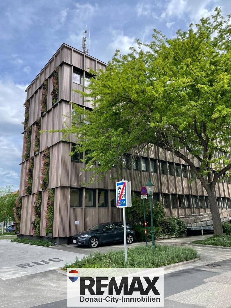 Seitenansicht des Gebäudes mit vertikalen Holzlamellen und üppiger Begrünung an der Fassade.